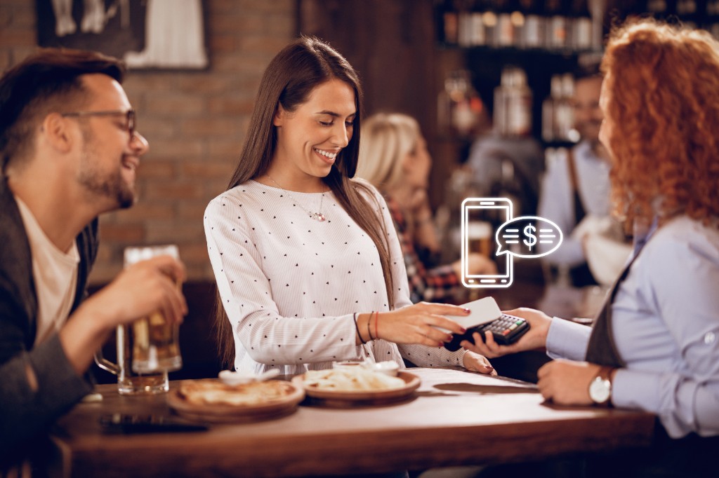 A customer paying her bill at a local restaurant with her phone